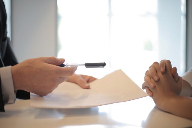 Agent handing pen to client