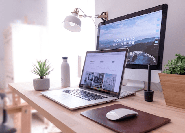 Multiple computers on a light-toned wood desk